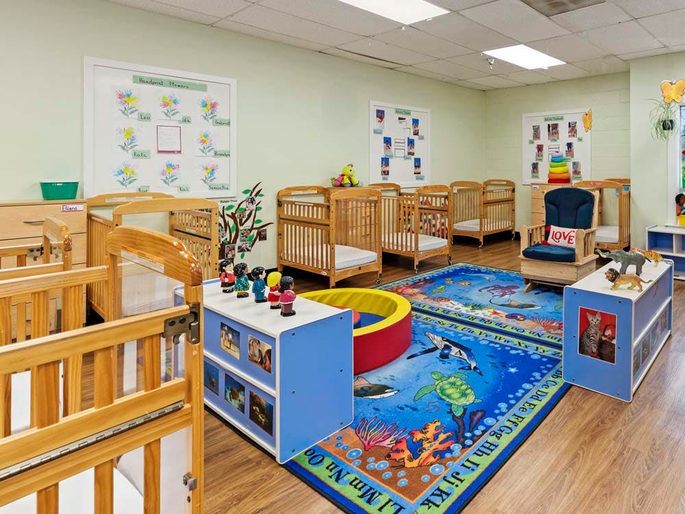 Cribs and play items in a brightly lit daycare or nursery room