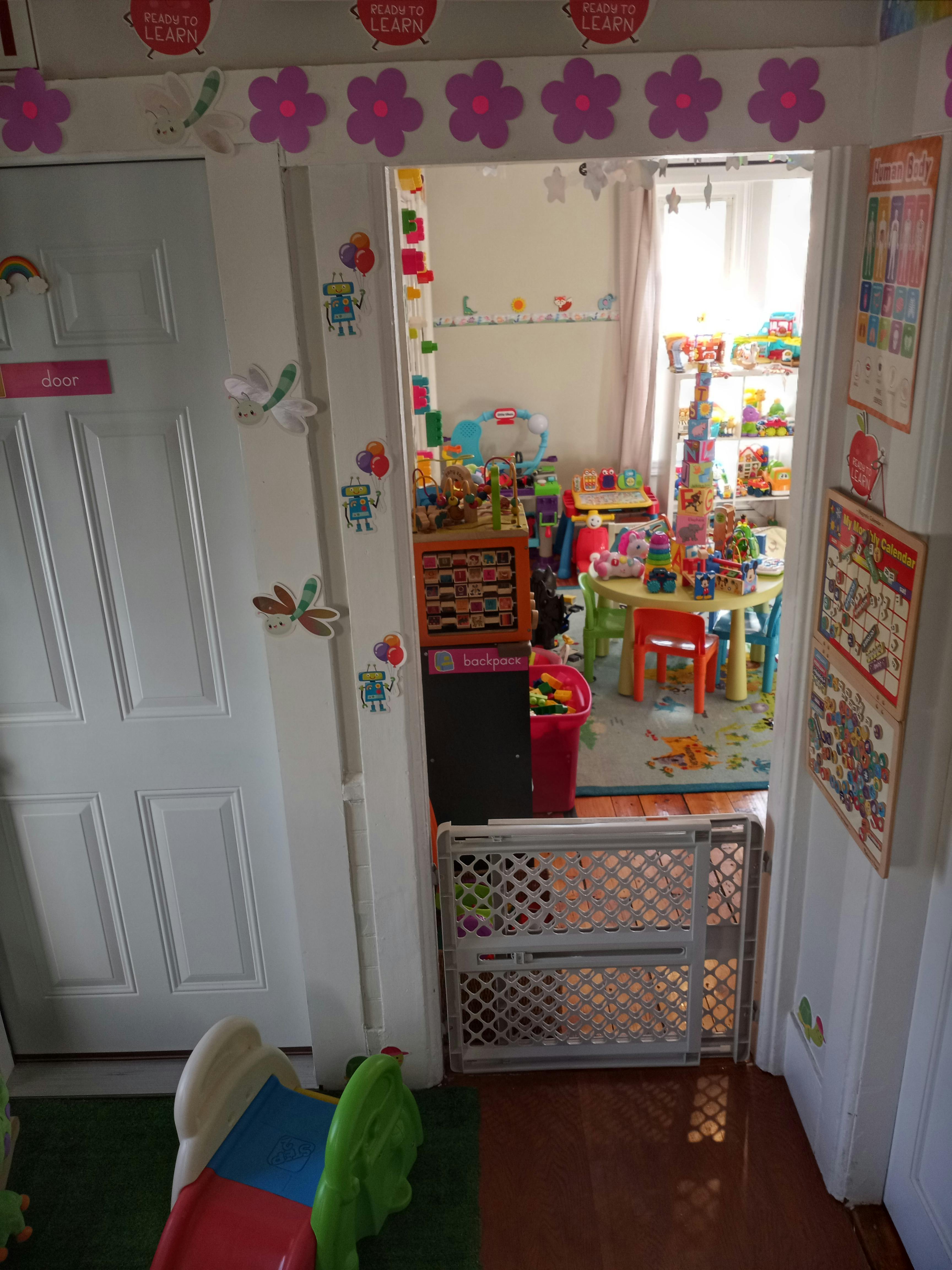 Doorway with baby gate leading into a colorful playroom filled with toys
