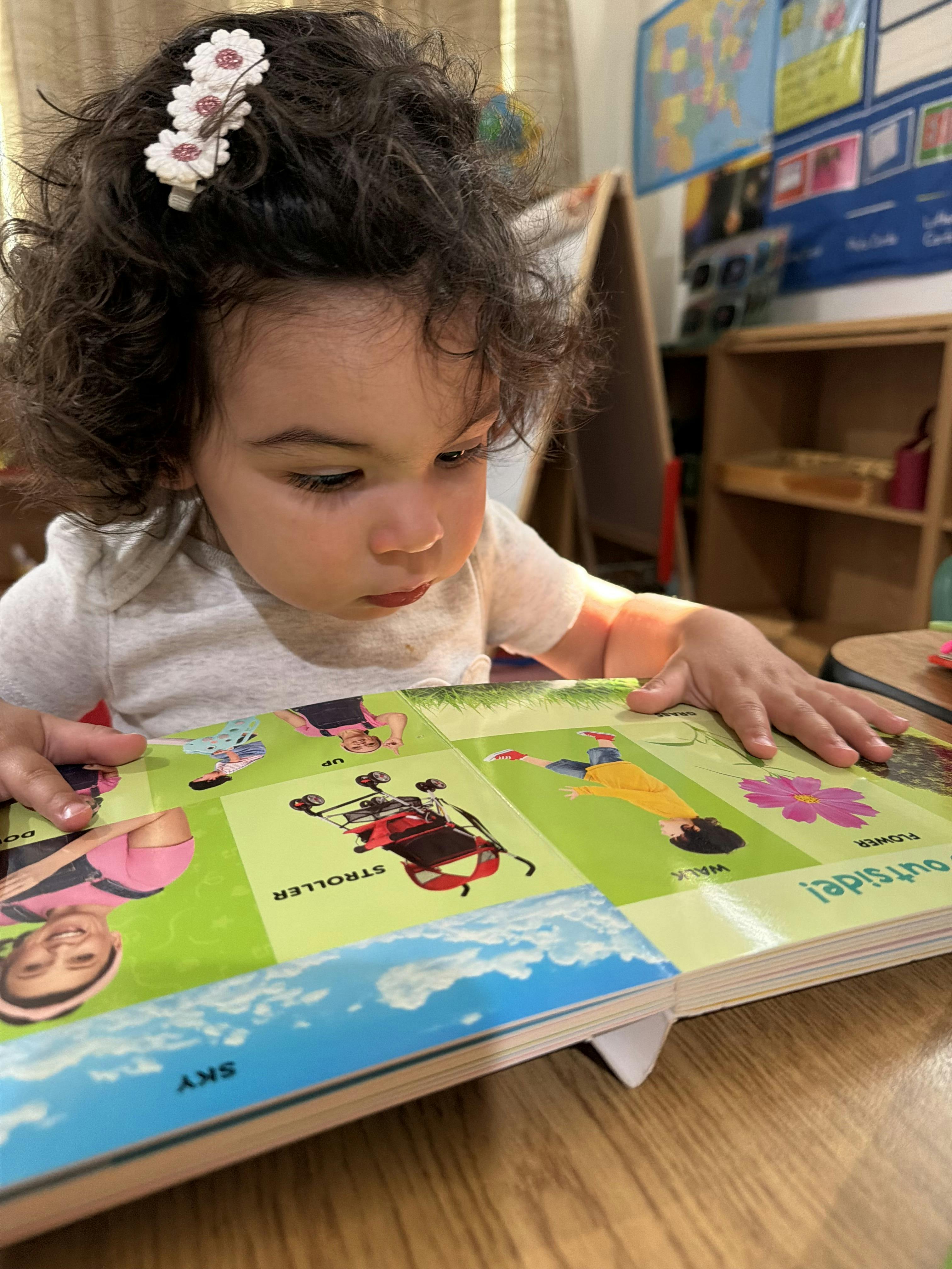 Child with curly hair looking down at a picture book