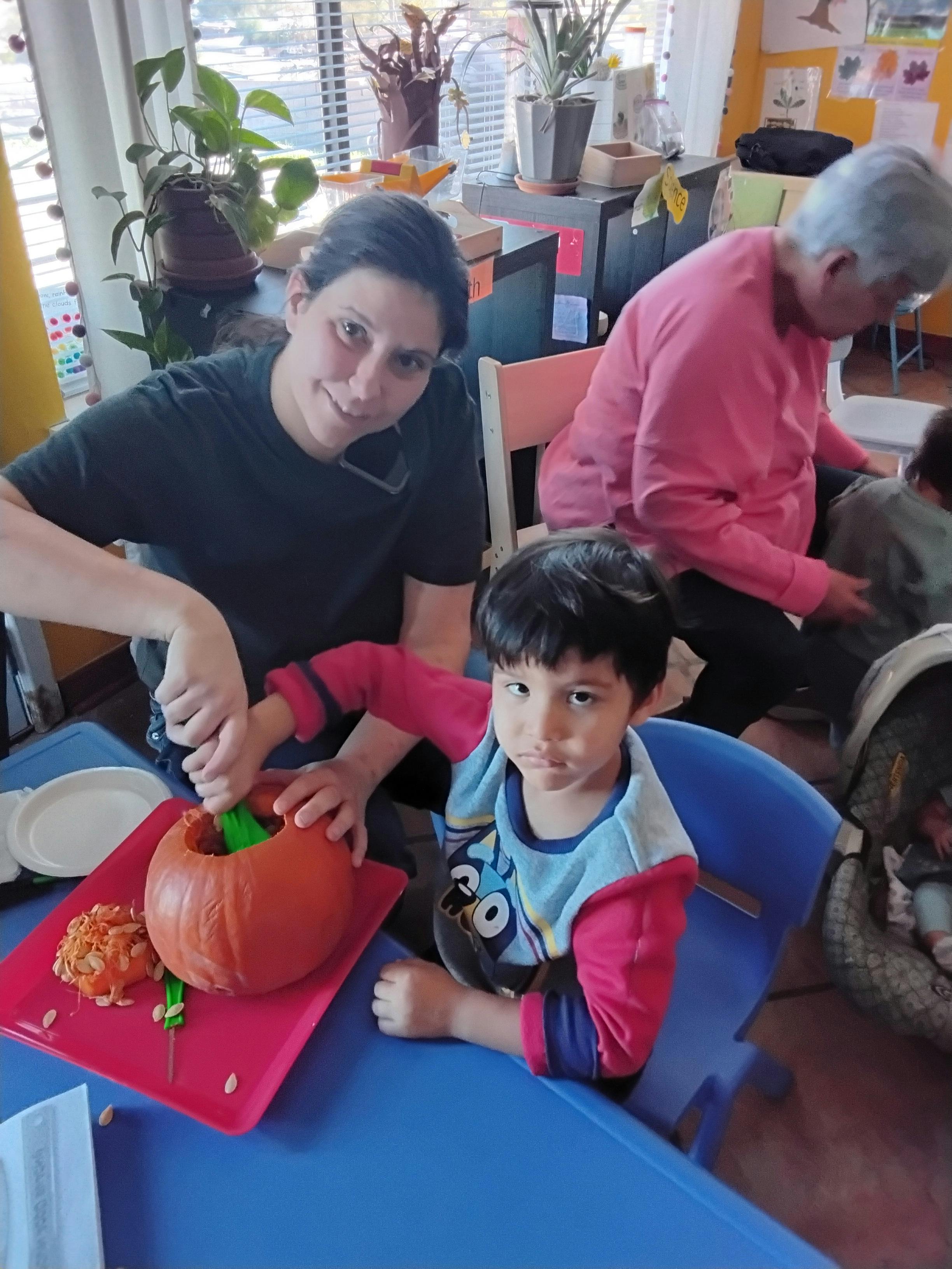 Adult and child carving a pumpkin at a table