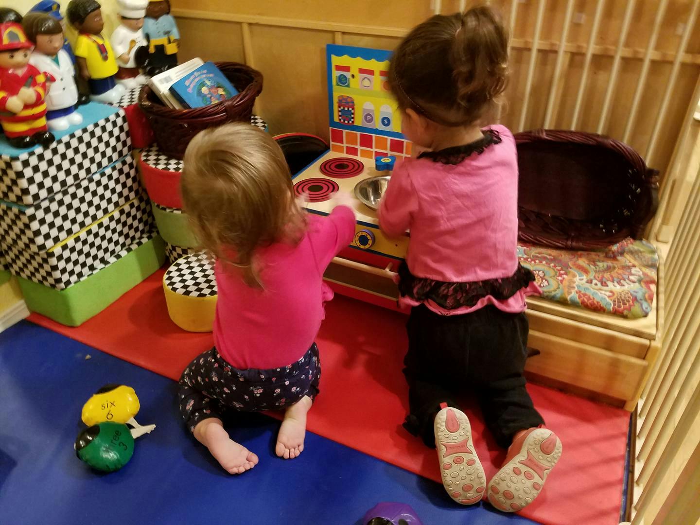 Two children playing with a toy kitchen set in a classroom