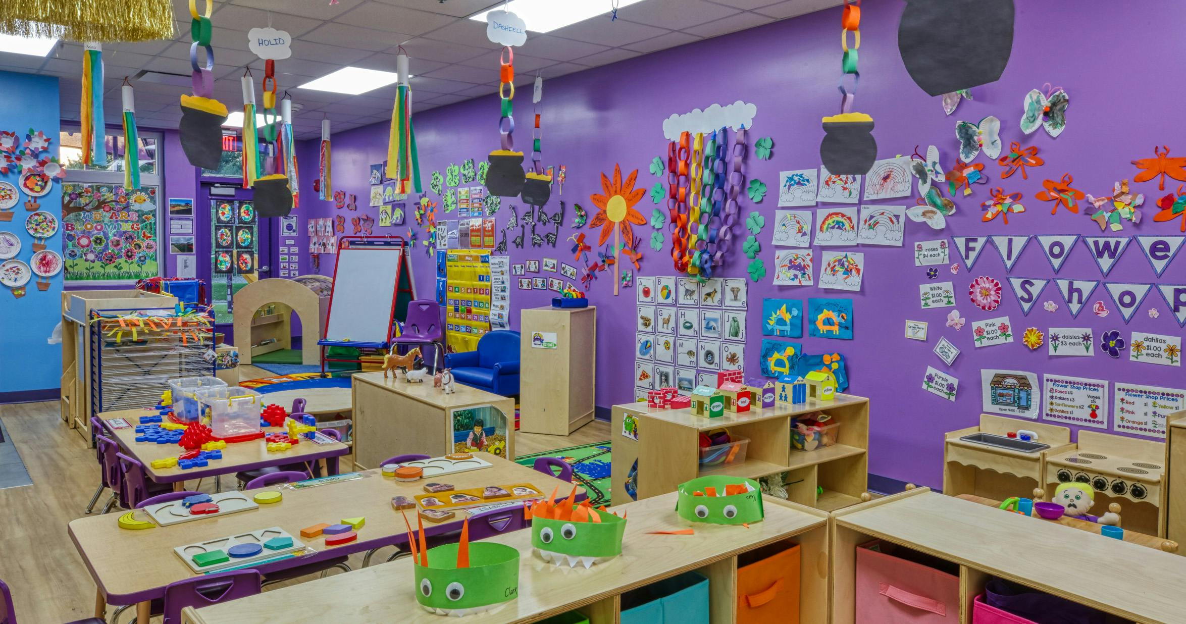 Colorful classroom with tables, chairs, and shelves filled with children's items