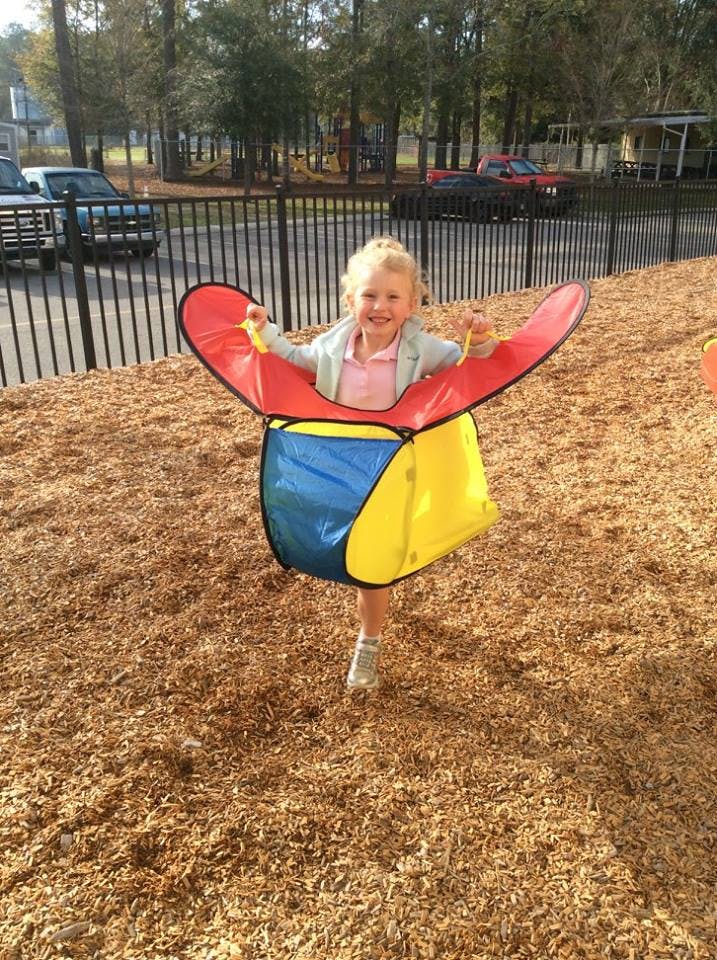Child standing in a colorful play tunnel on wood chips