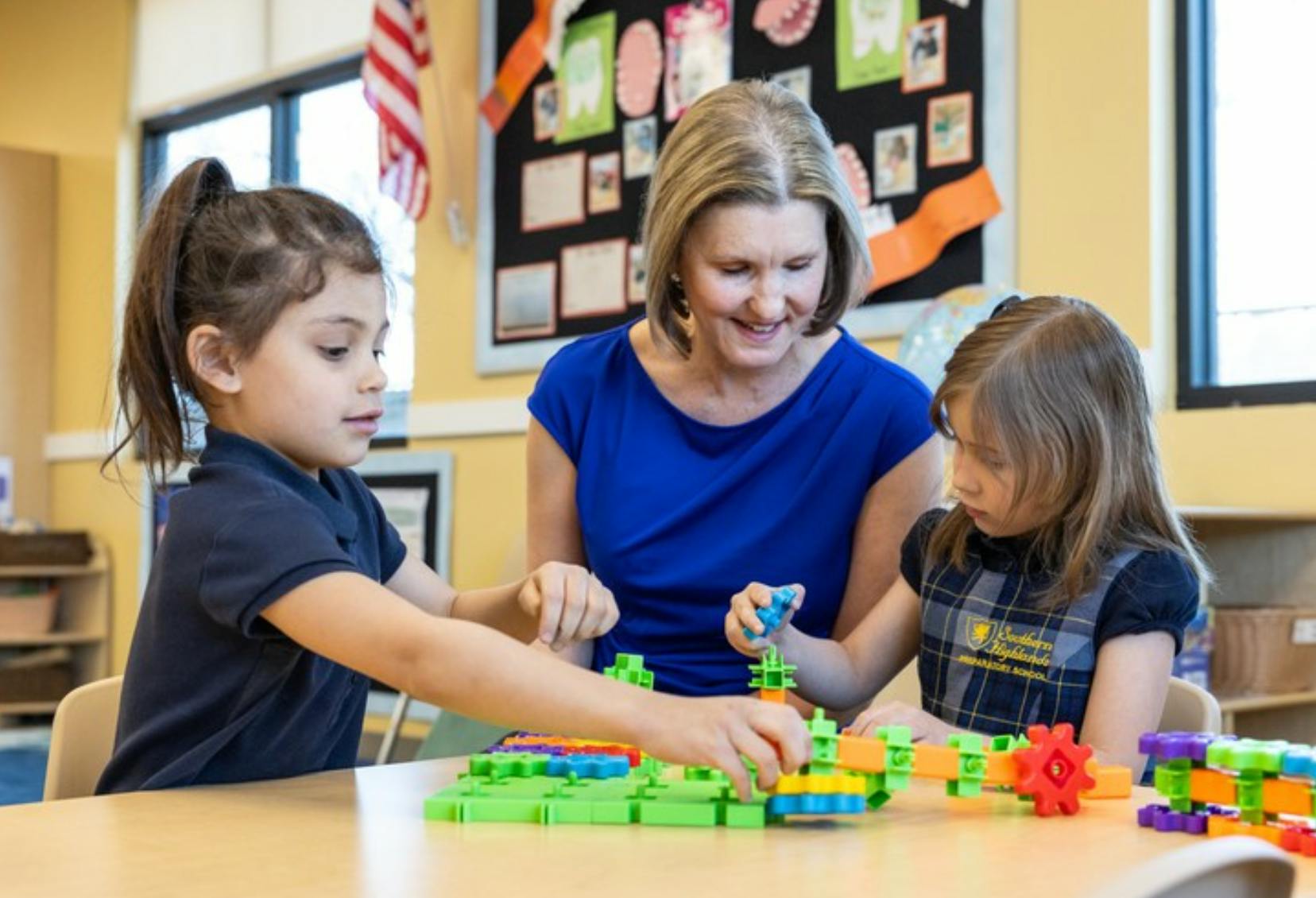 Adult and two children playing with building blocks at a table