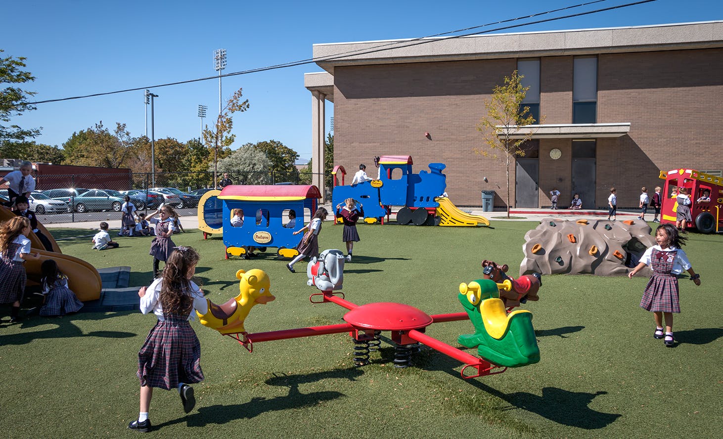 Children playing on a playground with a train, slides, and a merry-go-round