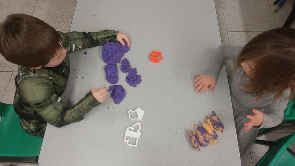 Two children playing with kinetic sand at a table