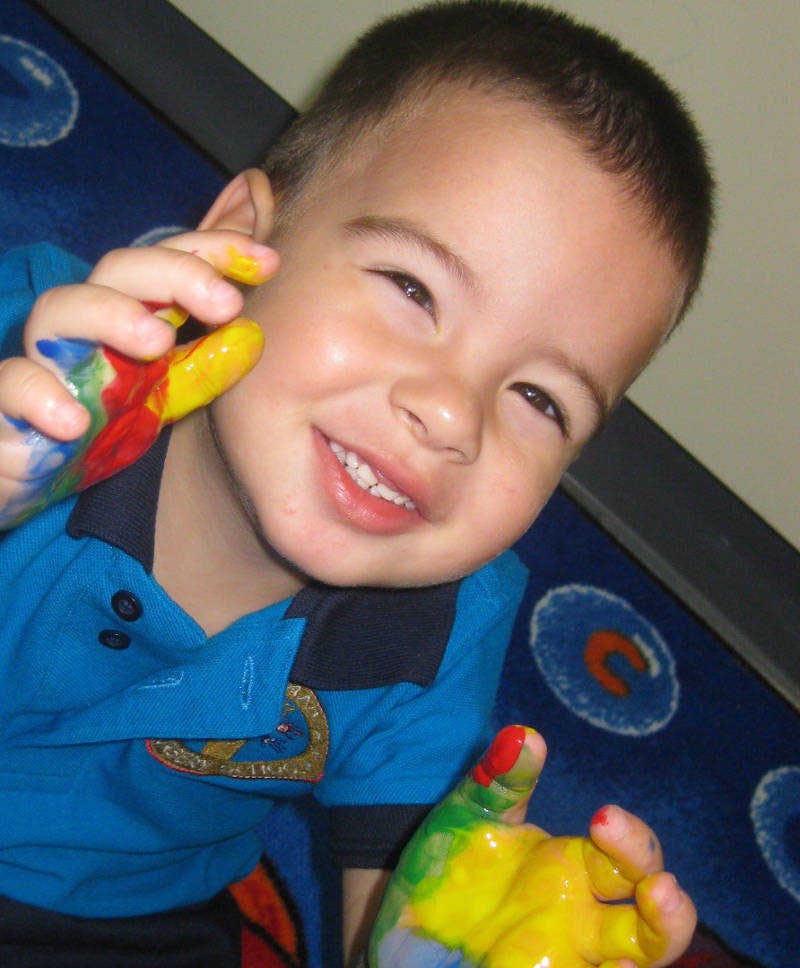 Child with hands covered in colorful paint