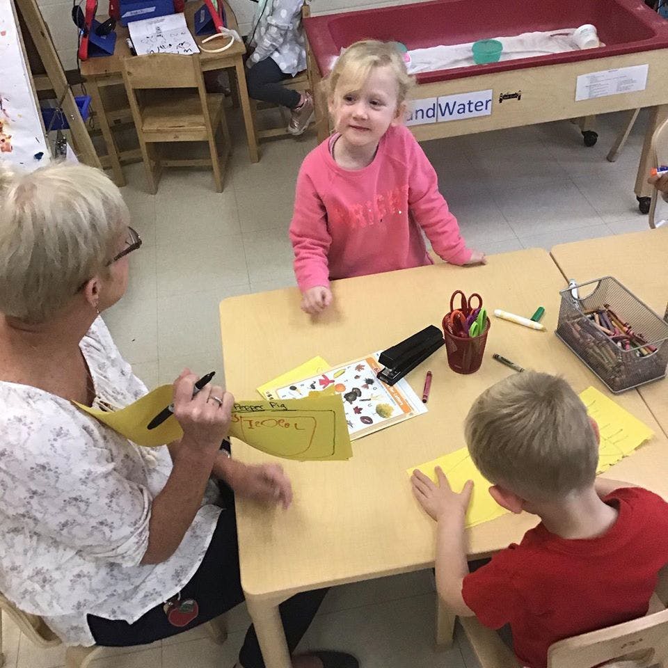Adult and two children at a table with papers and art supplies