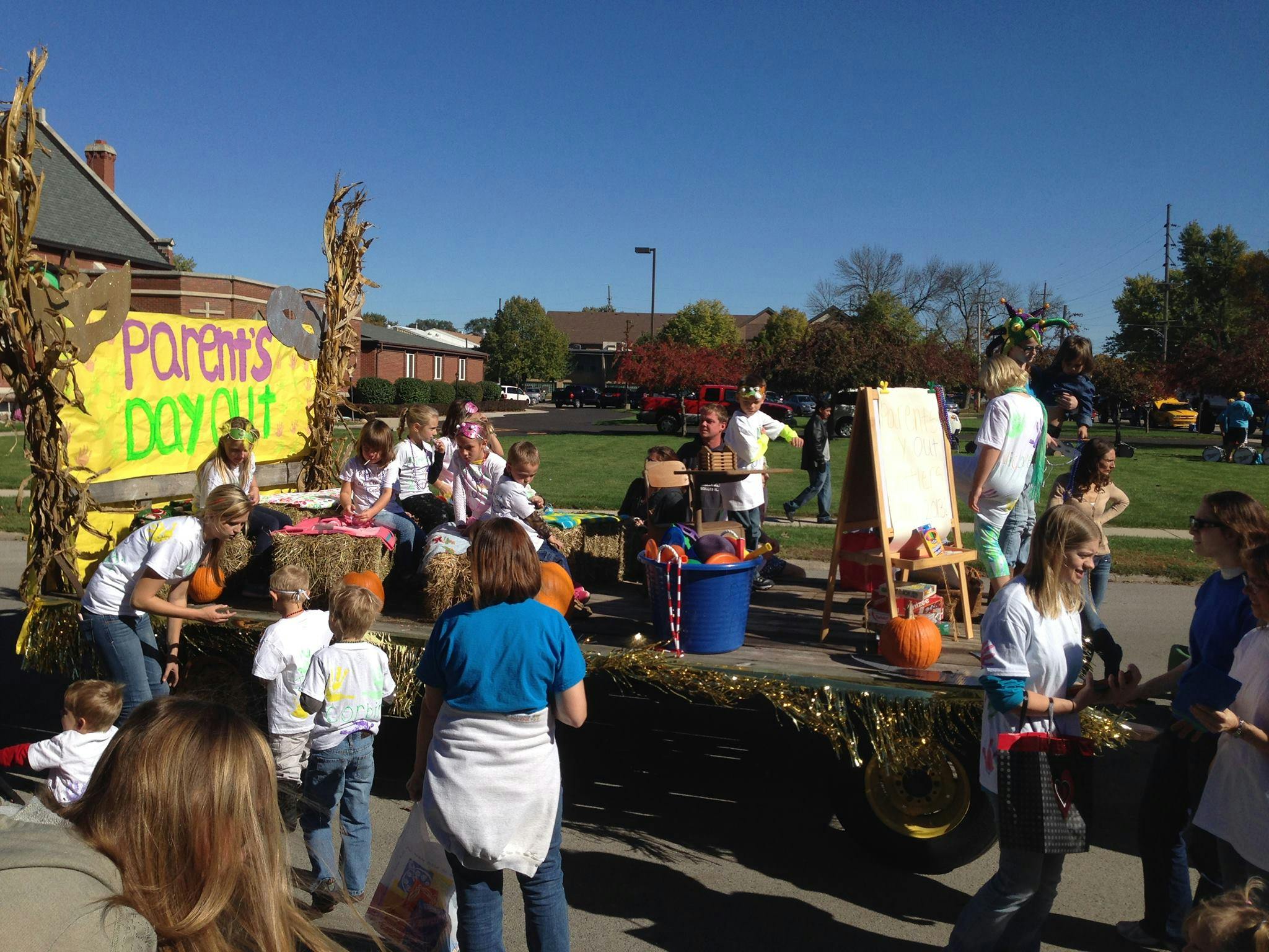 People on a parade float with a "Parents' Day Out" sign