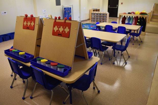 Two easels with paint pots on tables in a classroom