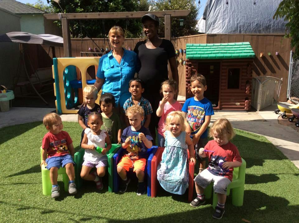 Two adults and a group of children posing outdoors