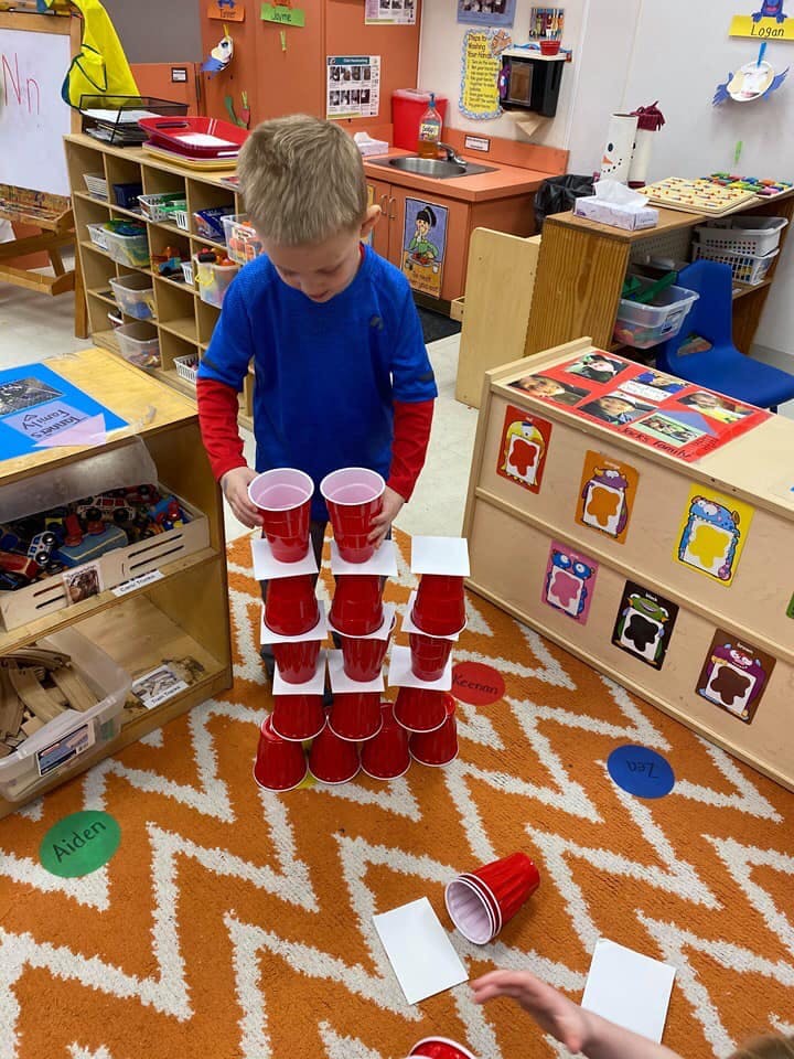 Child stacking red cups in a classroom