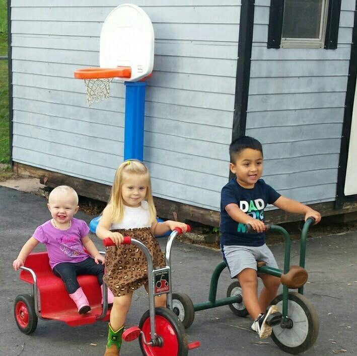 Three children with two tricycles and a wagon