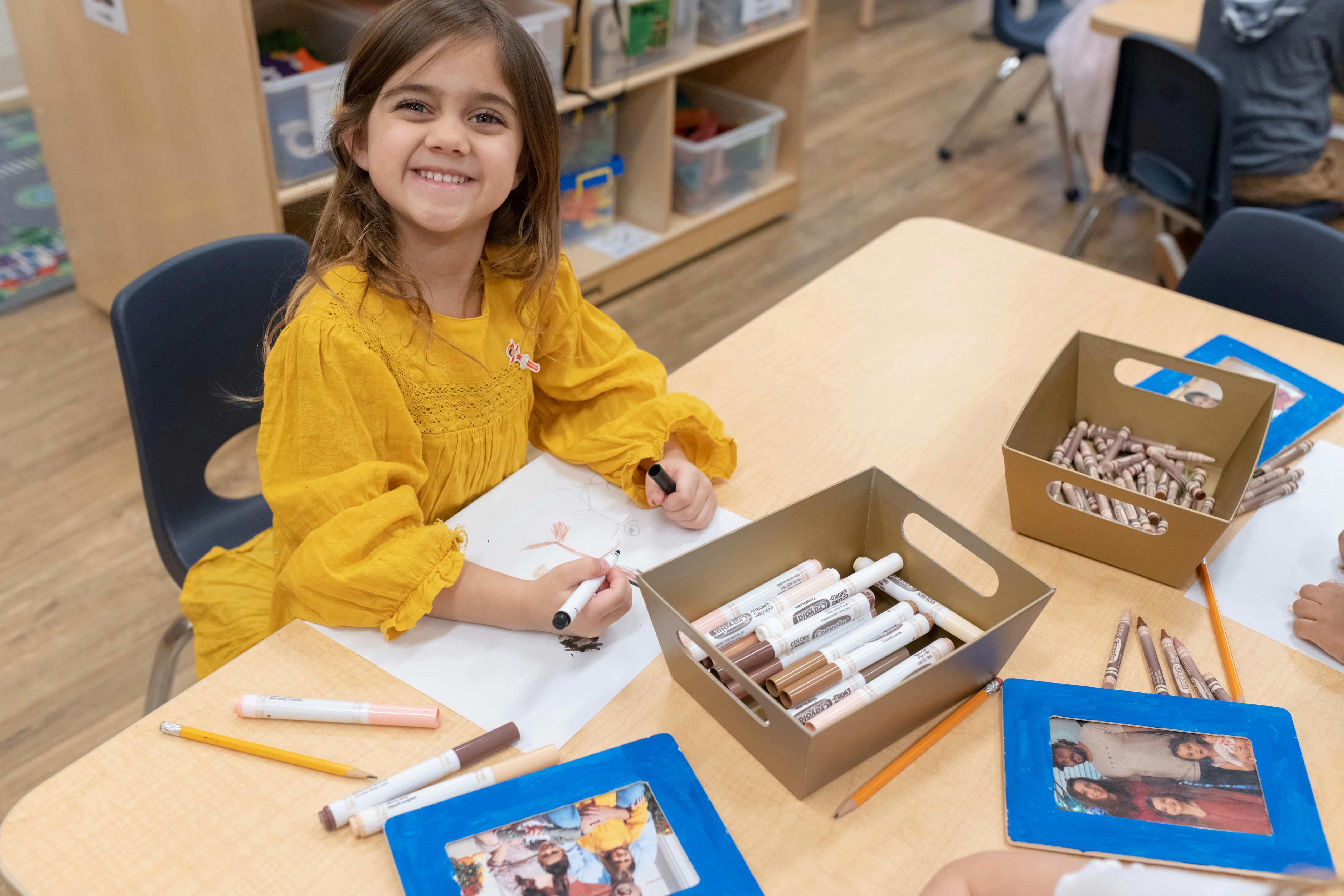 Child drawing at a table in a classroom