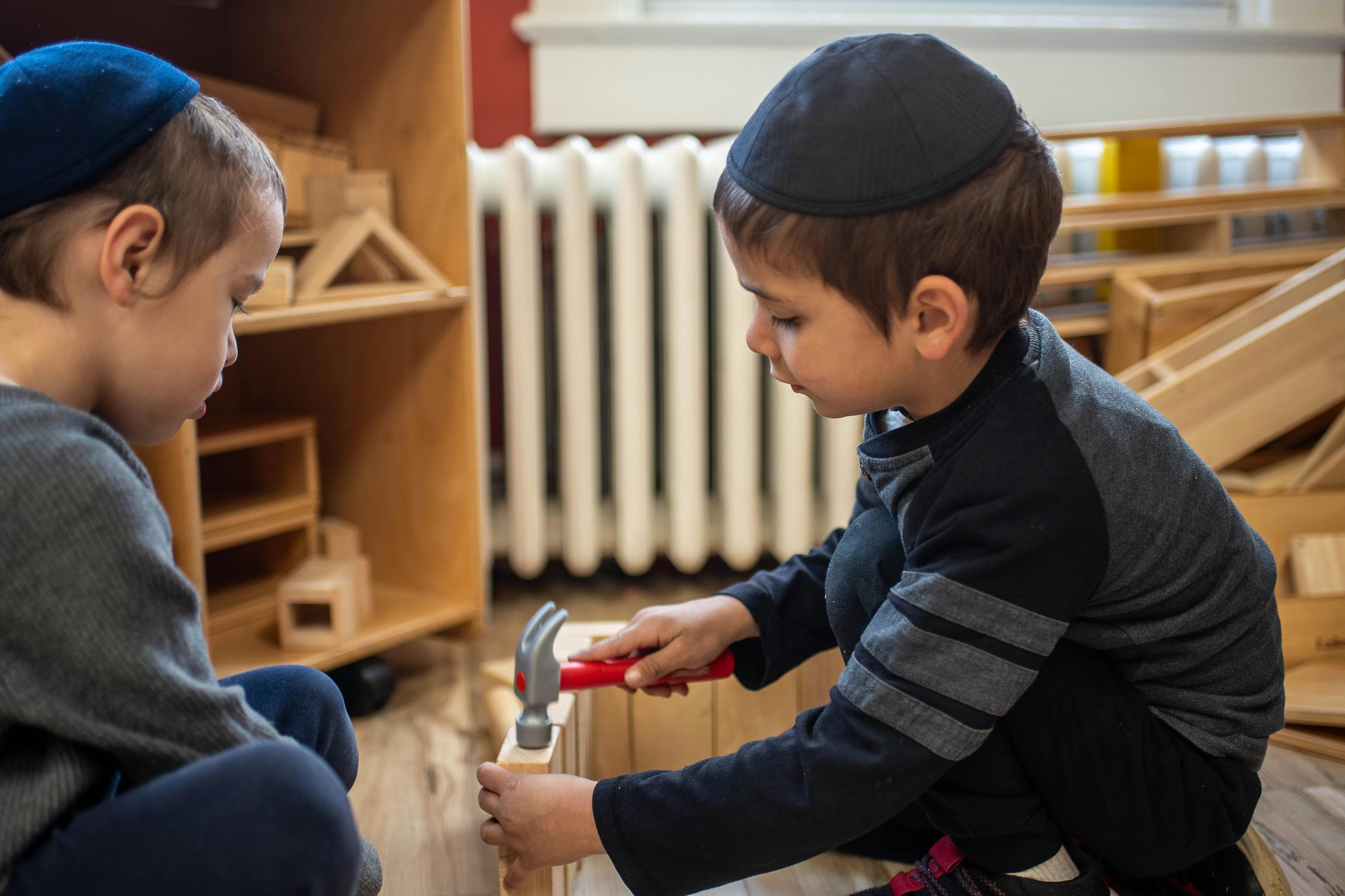 Two children playing with wooden blocks and a toy hammer