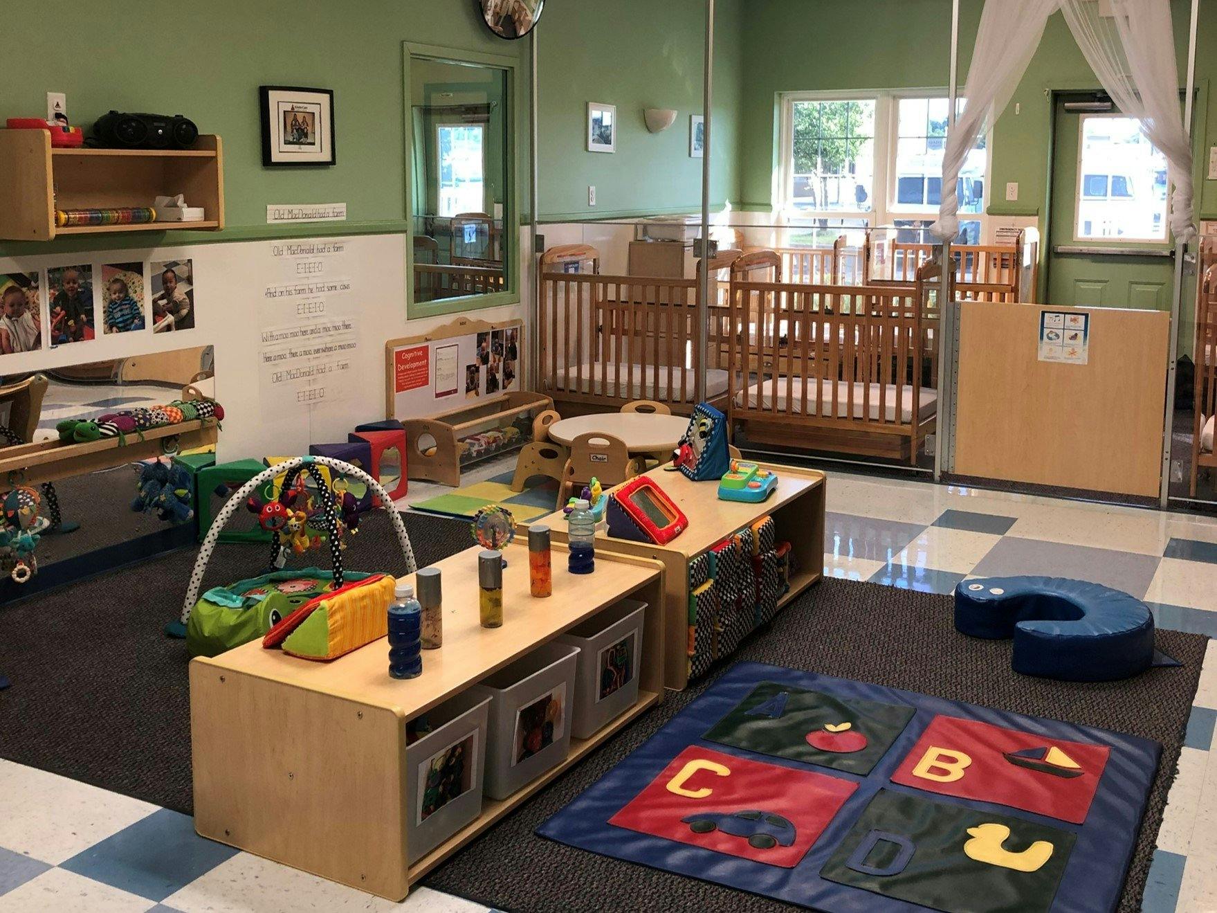 A colorful classroom with cribs, play mats, and learning toys