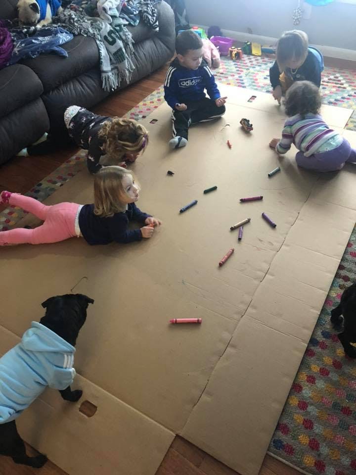 Children and a dog on a large piece of cardboard with crayons
