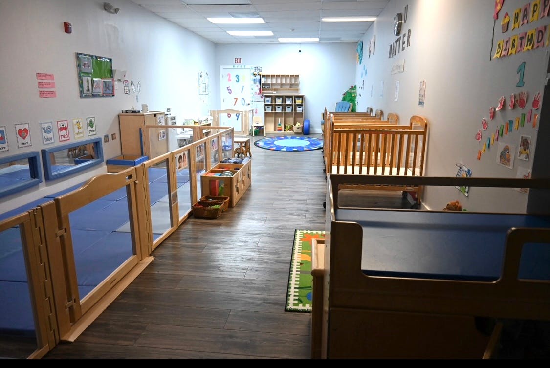 Empty daycare room with cribs and play areas