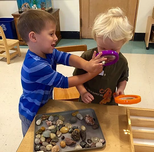 Two children examining rocks with magnifying glasses