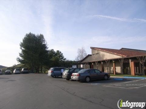 Cars parked in a lot next to a building with a brown roof
