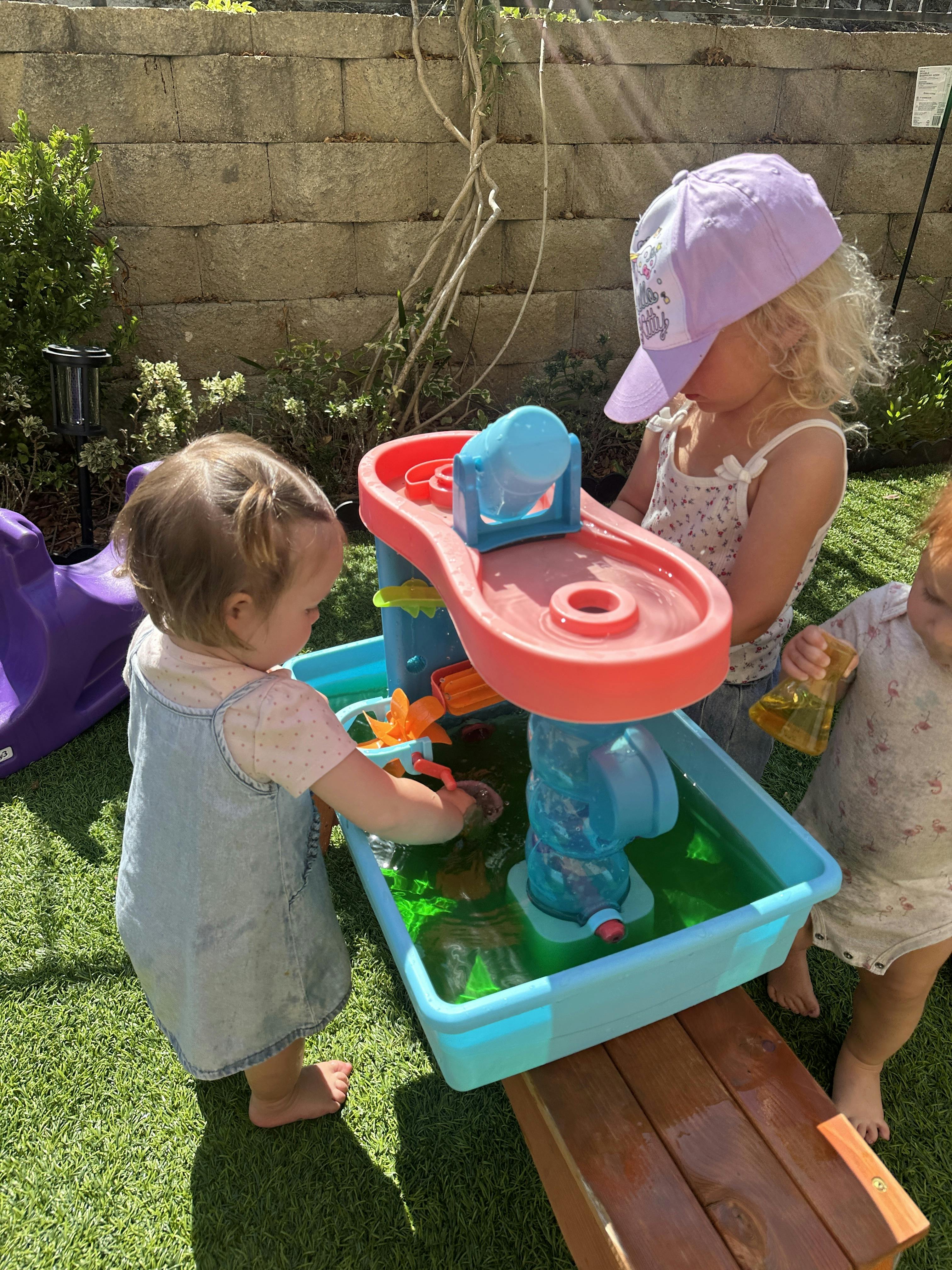 Three children playing with a water table outdoors