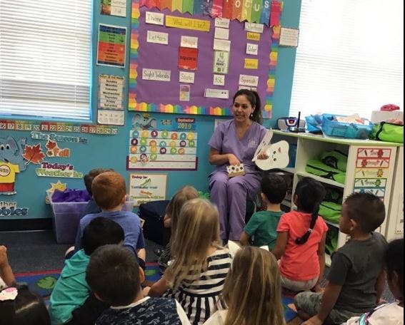 Person in scrubs teaching children in a classroom