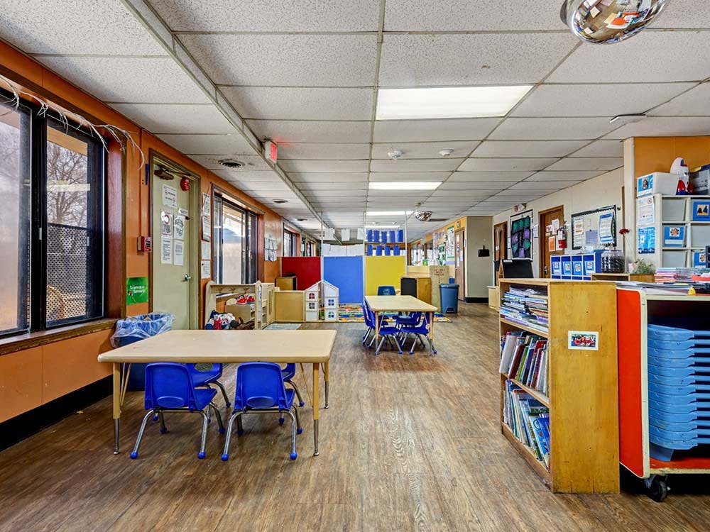 Classroom with small tables, chairs, and shelves