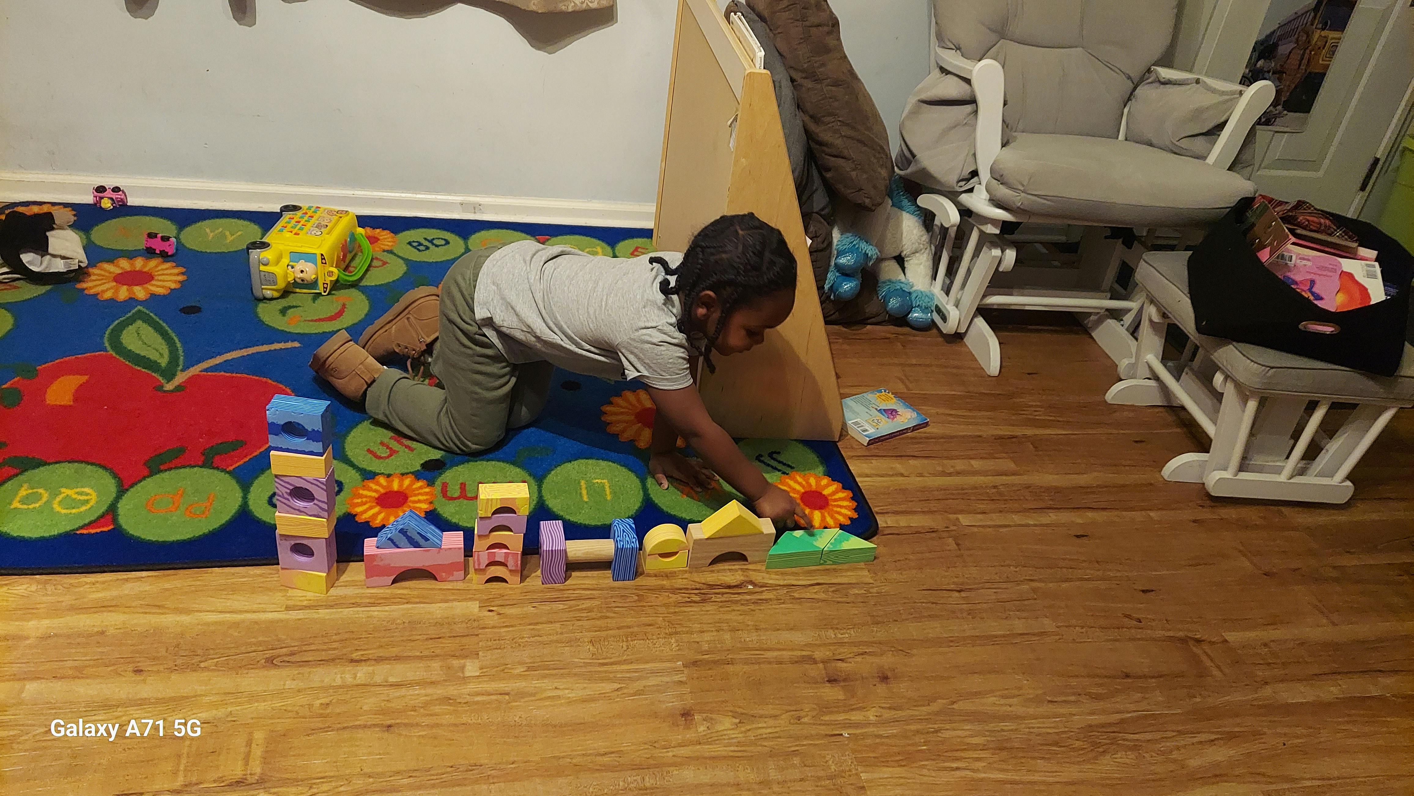 Child playing with colorful building blocks on a rug
