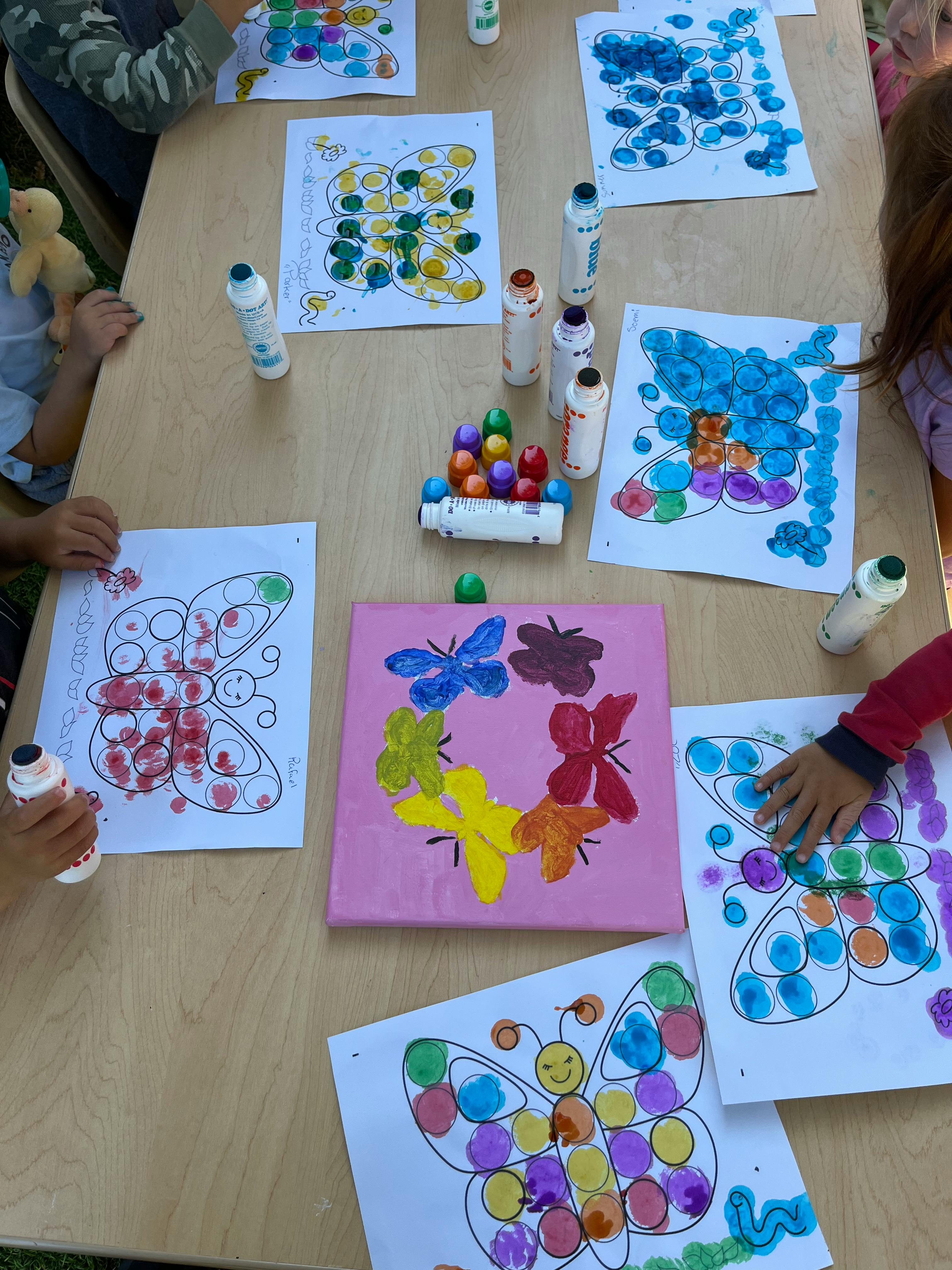 Children's hands painting butterfly pictures with dot markers
