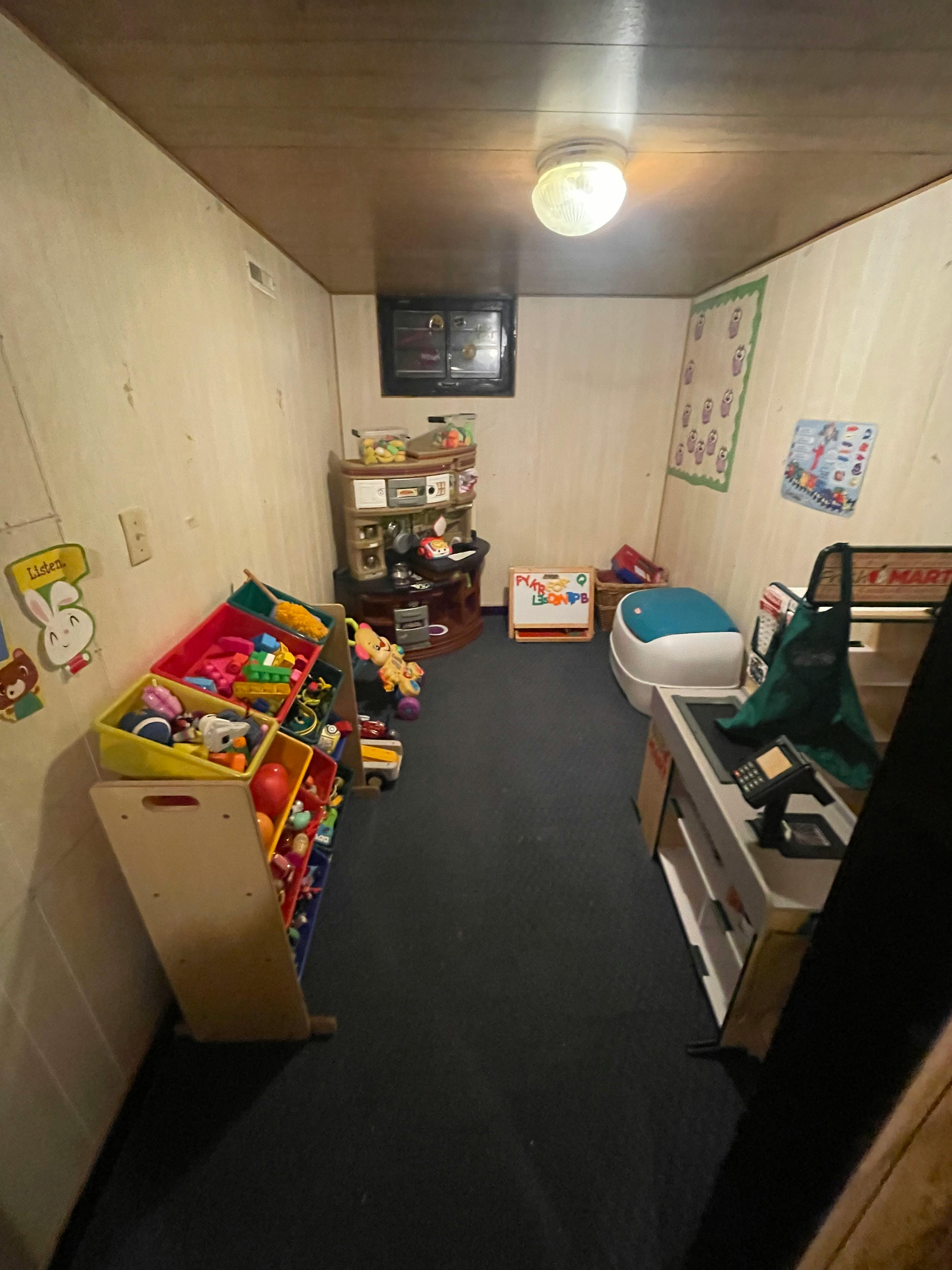 Playroom with toy storage, play kitchen, and small window