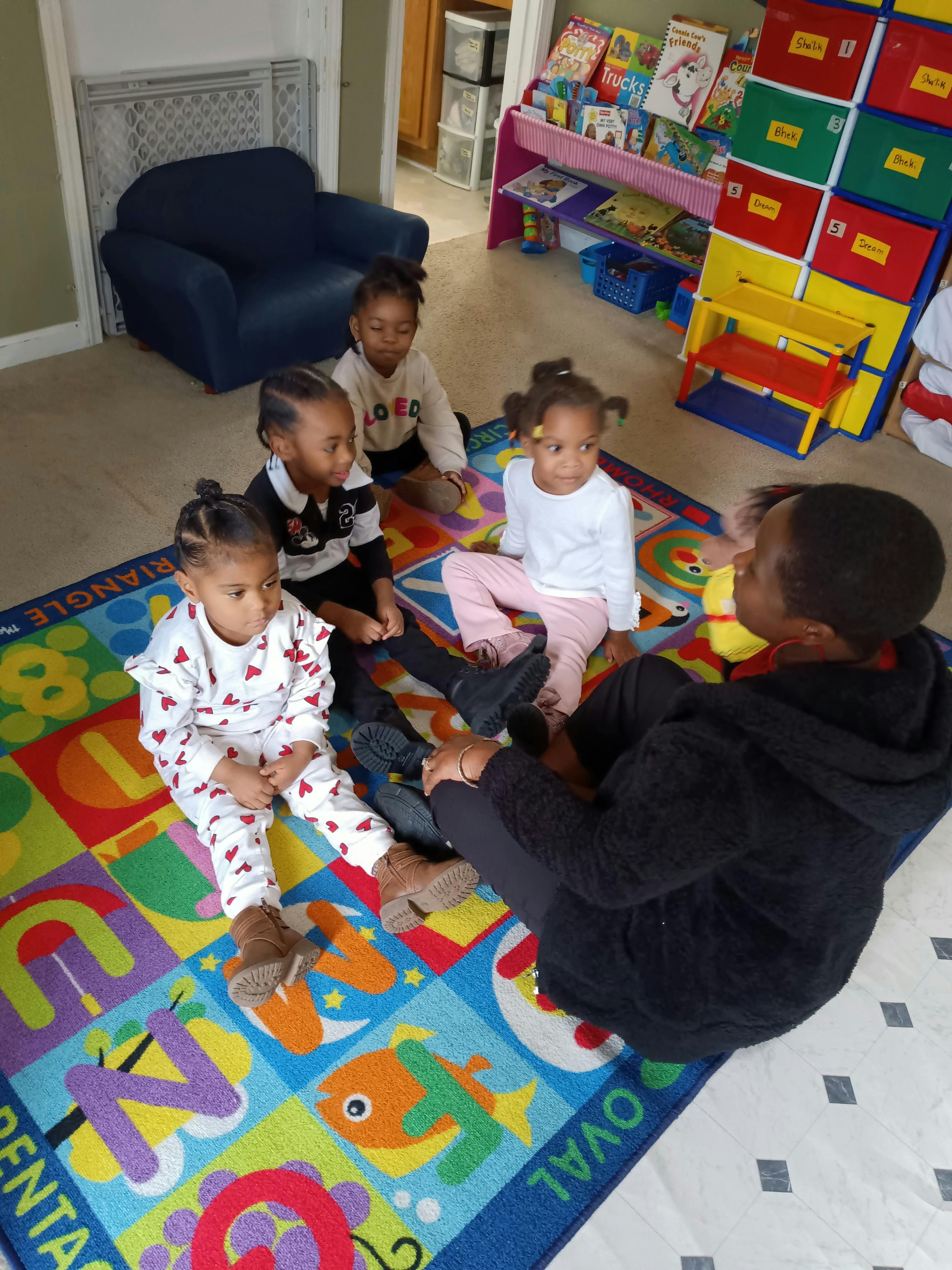 Adult and four children sitting on a colorful rug