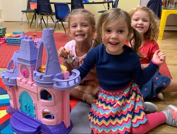 Three children playing with a toy castle