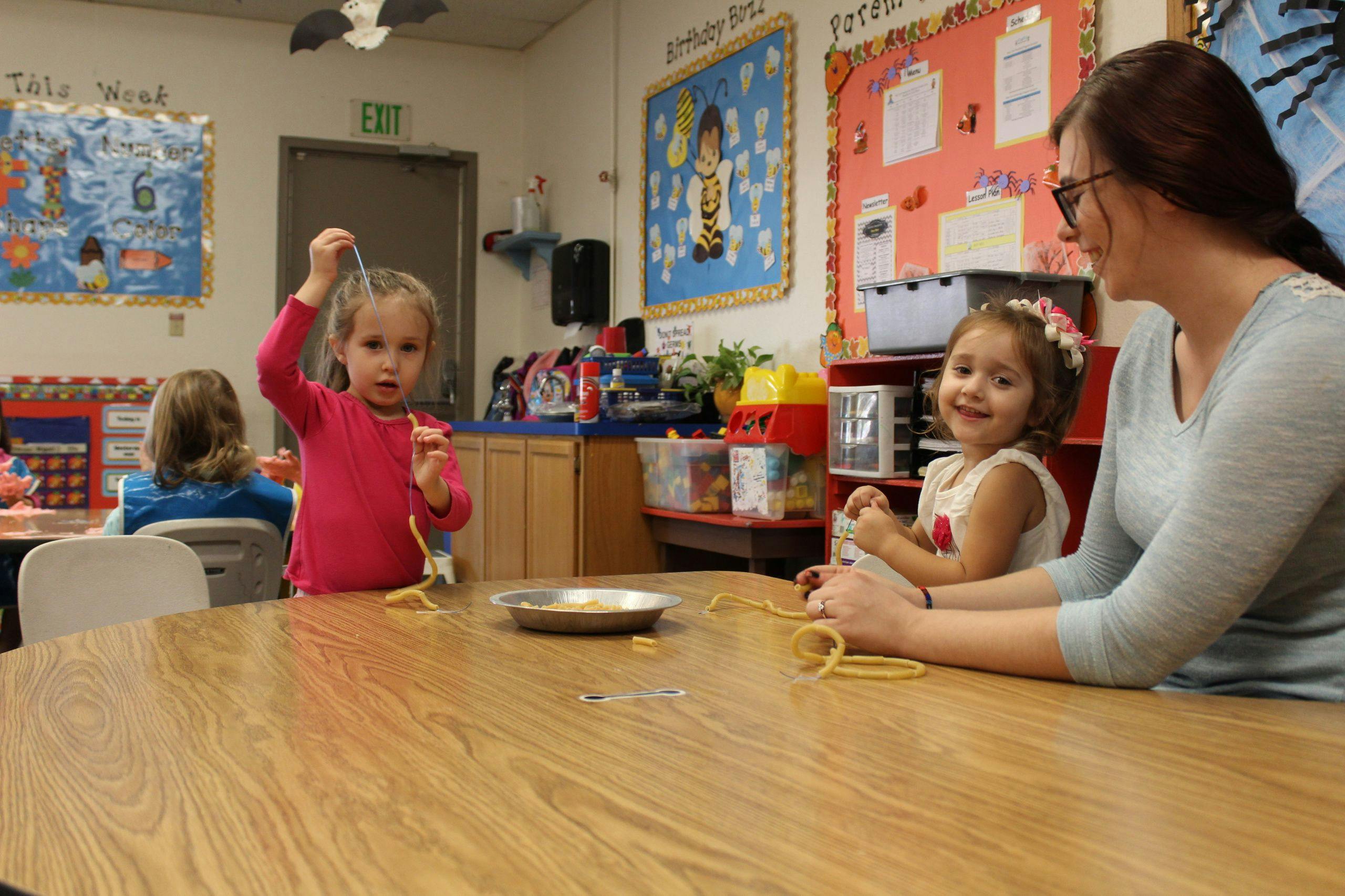 Adult and two children at a table in a classroom