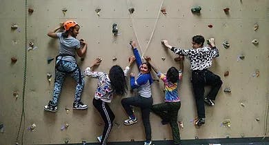 Five people rock climbing on an indoor wall