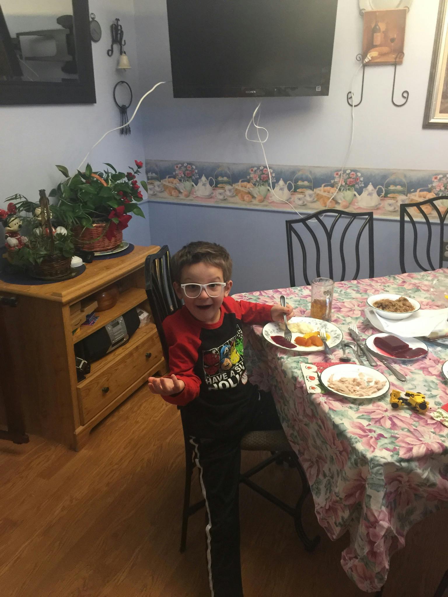 Child in glasses sitting at a table with plates of food
