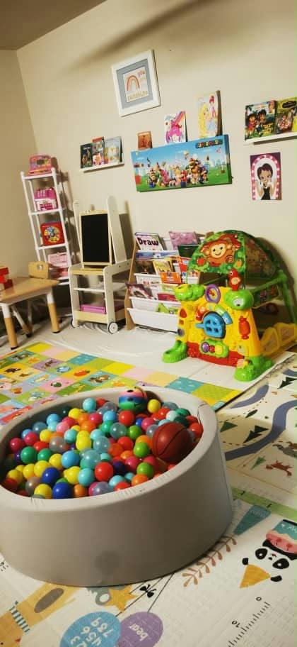 Child's playroom featuring a ball pit, activity center, and book storage shelves