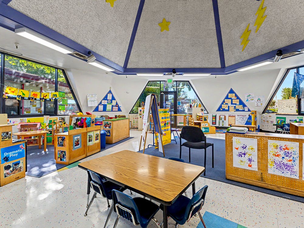 Empty classroom with student artwork, tables, and chairs