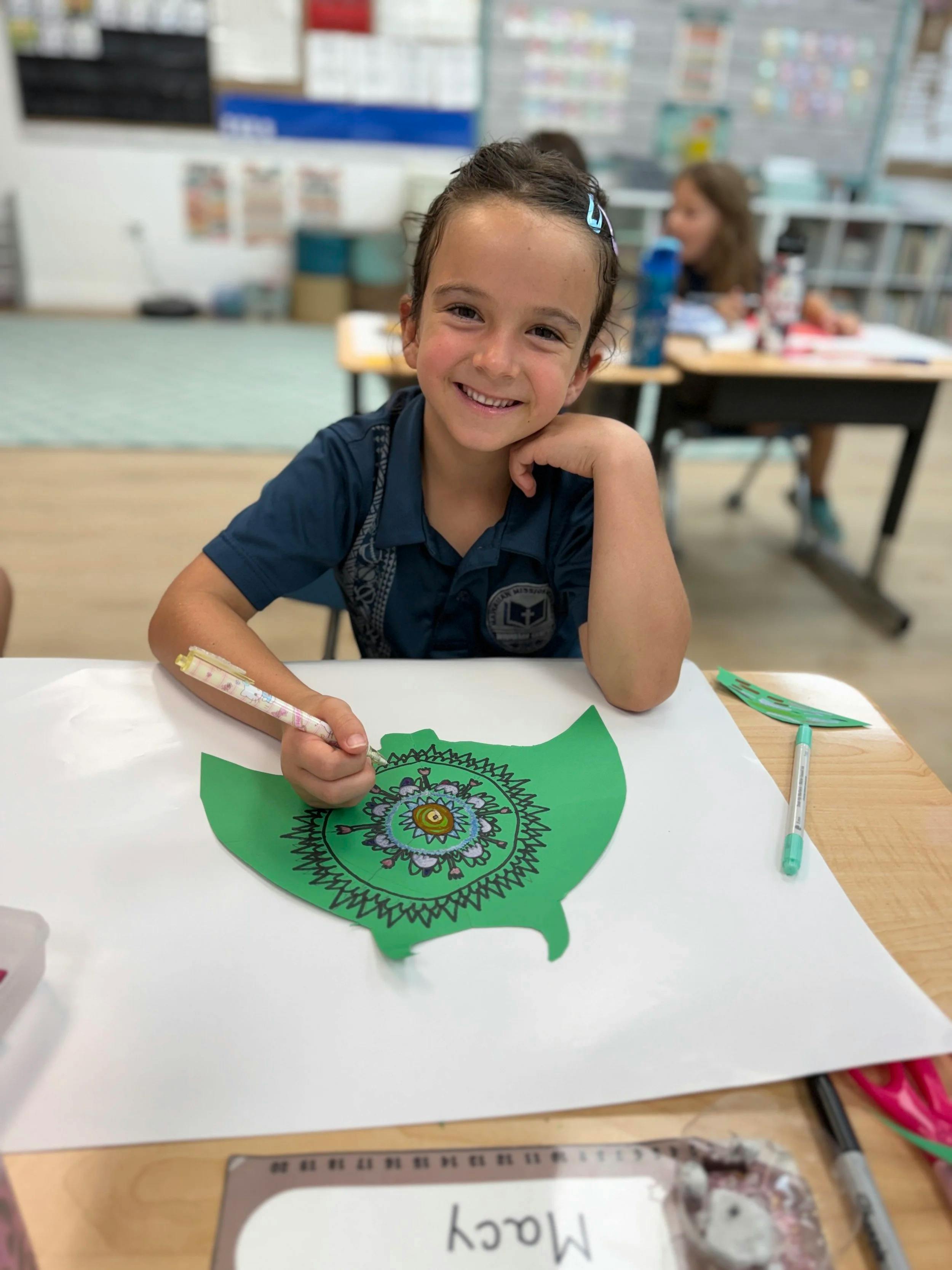 Child drawing a mandala on green paper at a school desk