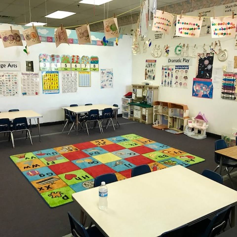 Classroom with tables, chairs, and a colorful alphabet rug