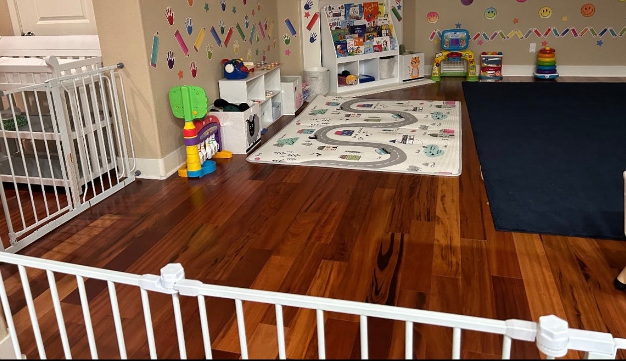 Playroom with hardwood floor, white baby gate, and play mat