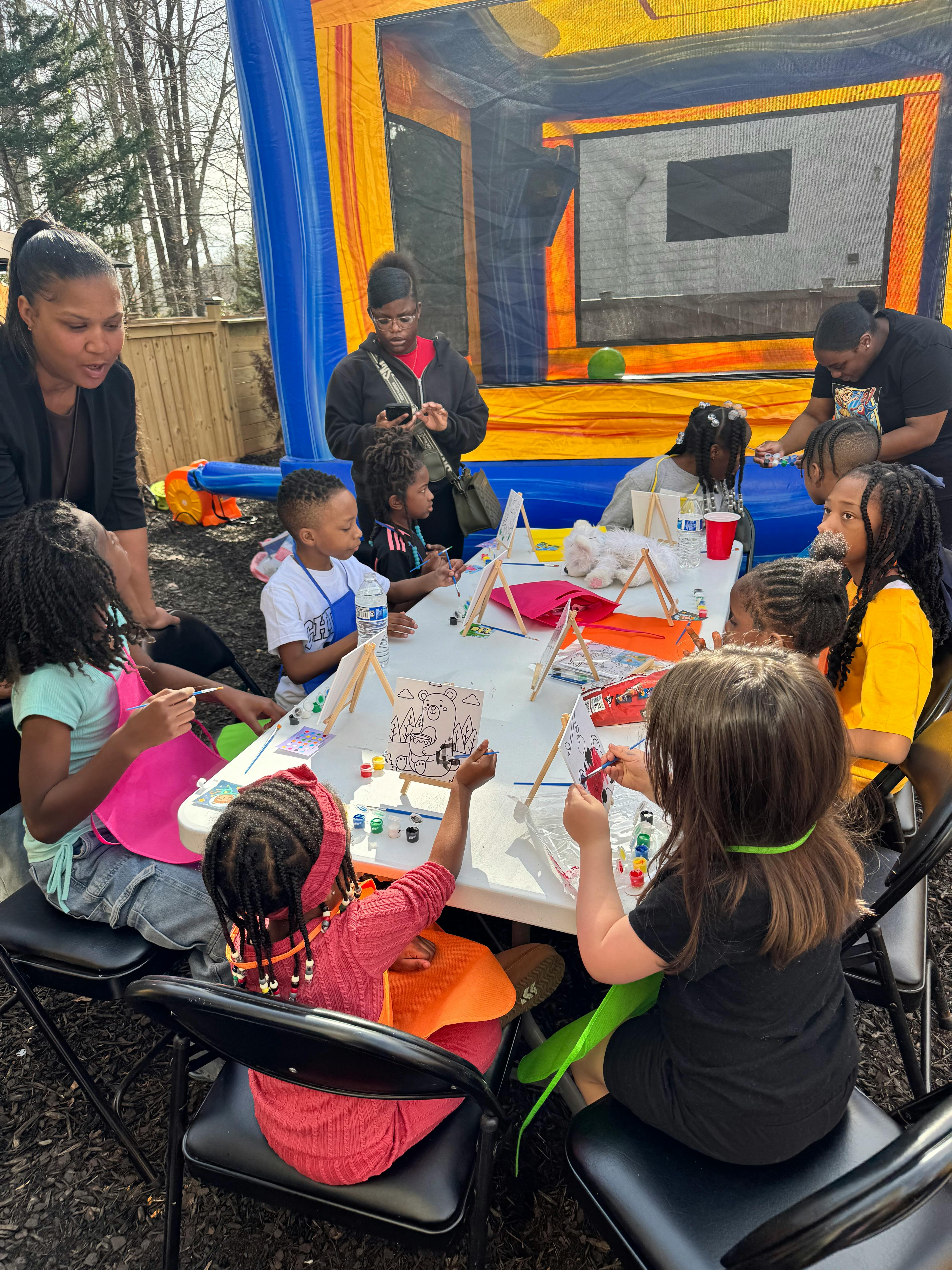People and children painting at a table outdoors