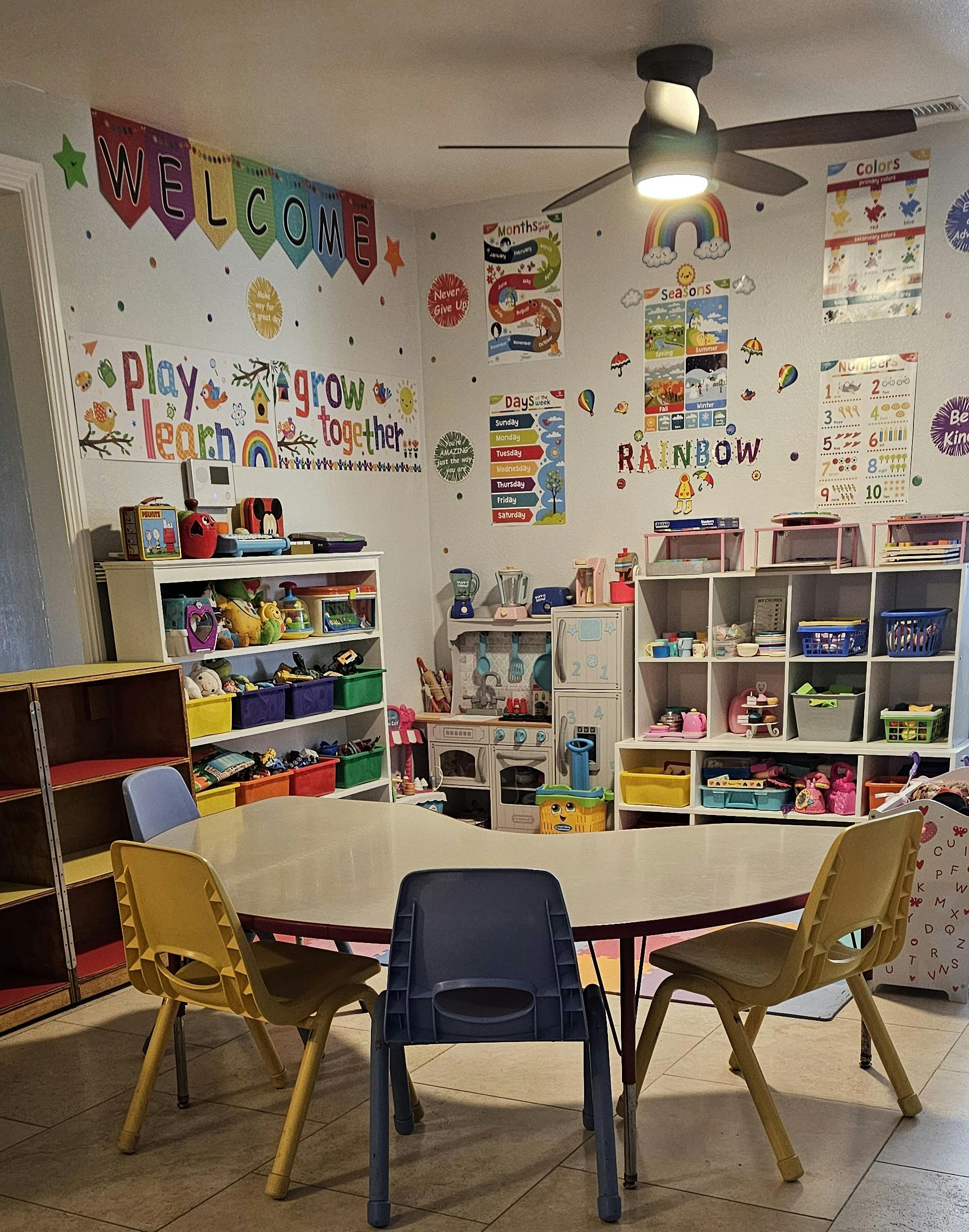 Classroom with a table and chairs, shelves with toys, and wall decorations