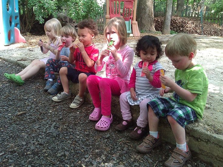 Group of children sitting outdoors eating popsicles