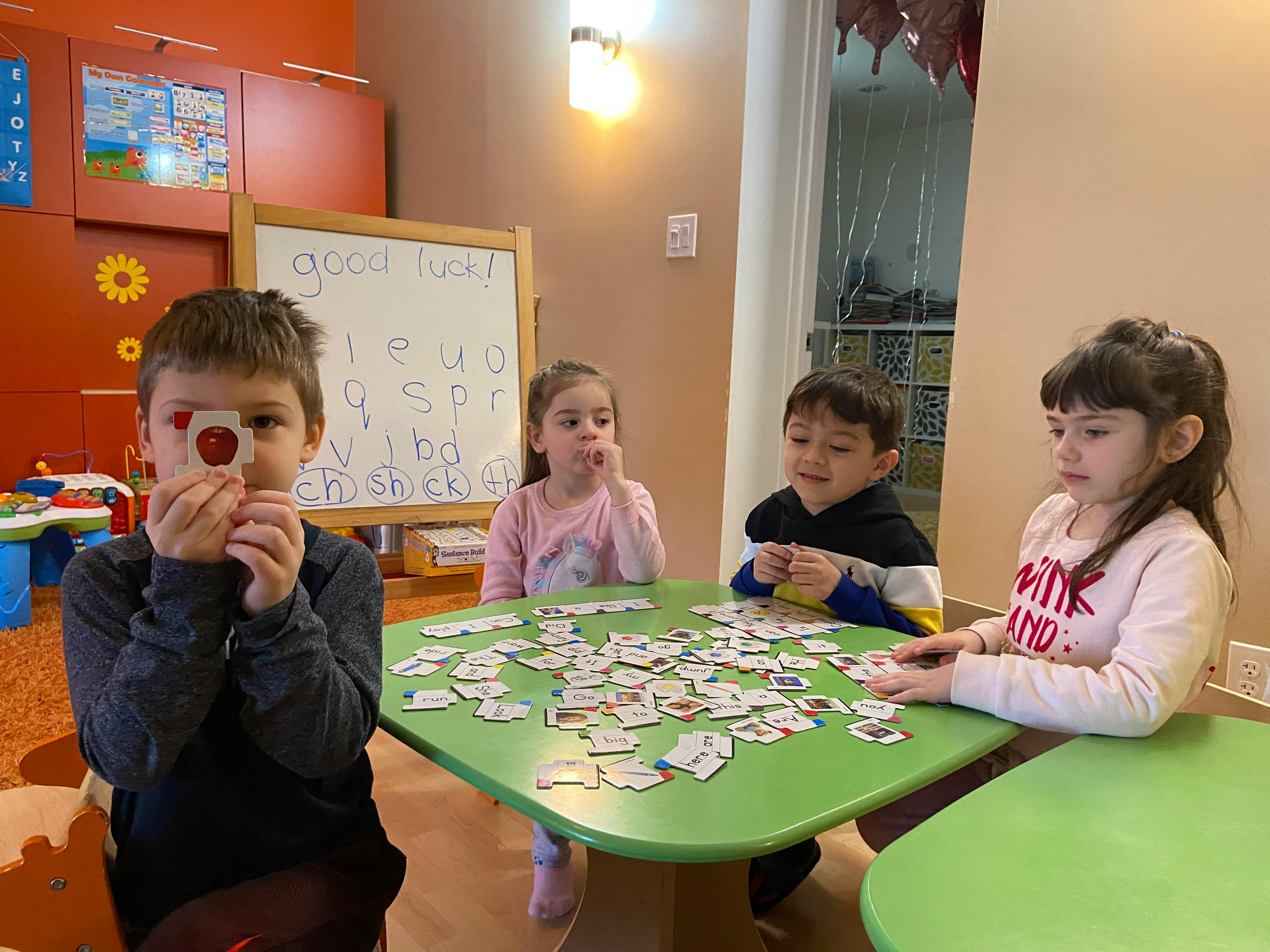 Four children playing a card game at a green table