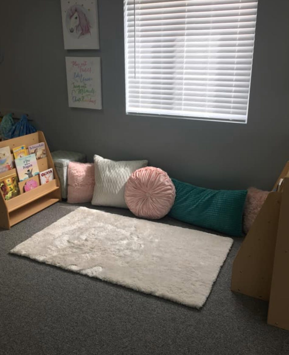 Reading nook with a rug, pillows, and a bookshelf