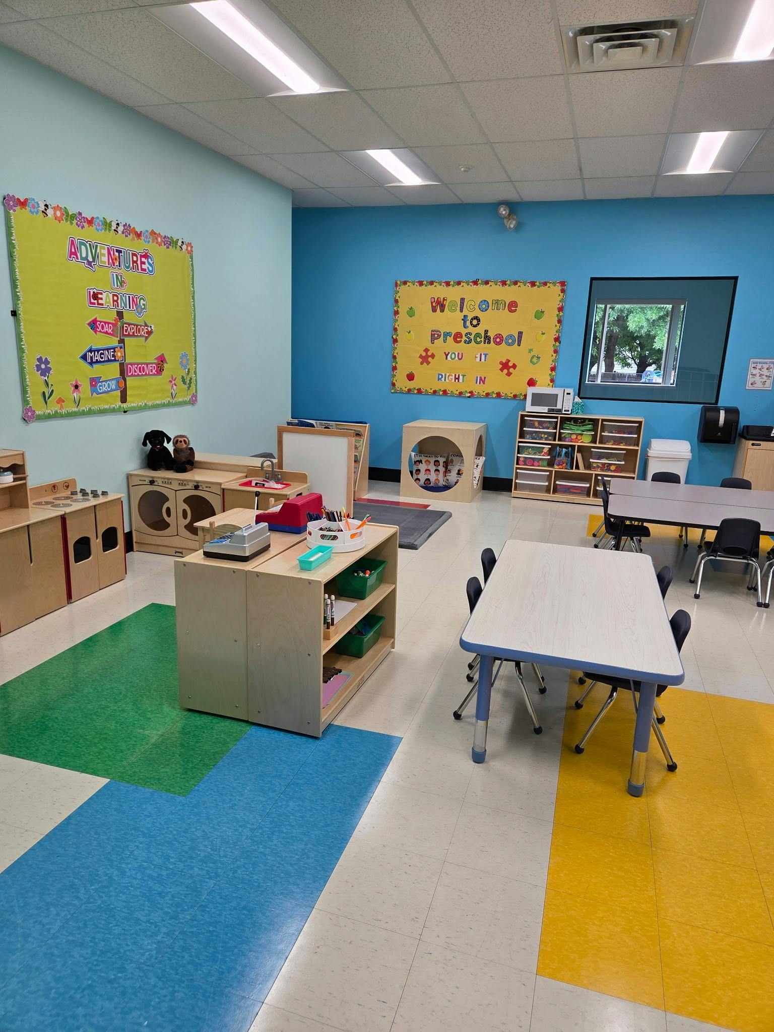 Empty preschool classroom with children's furniture and educational wall signs