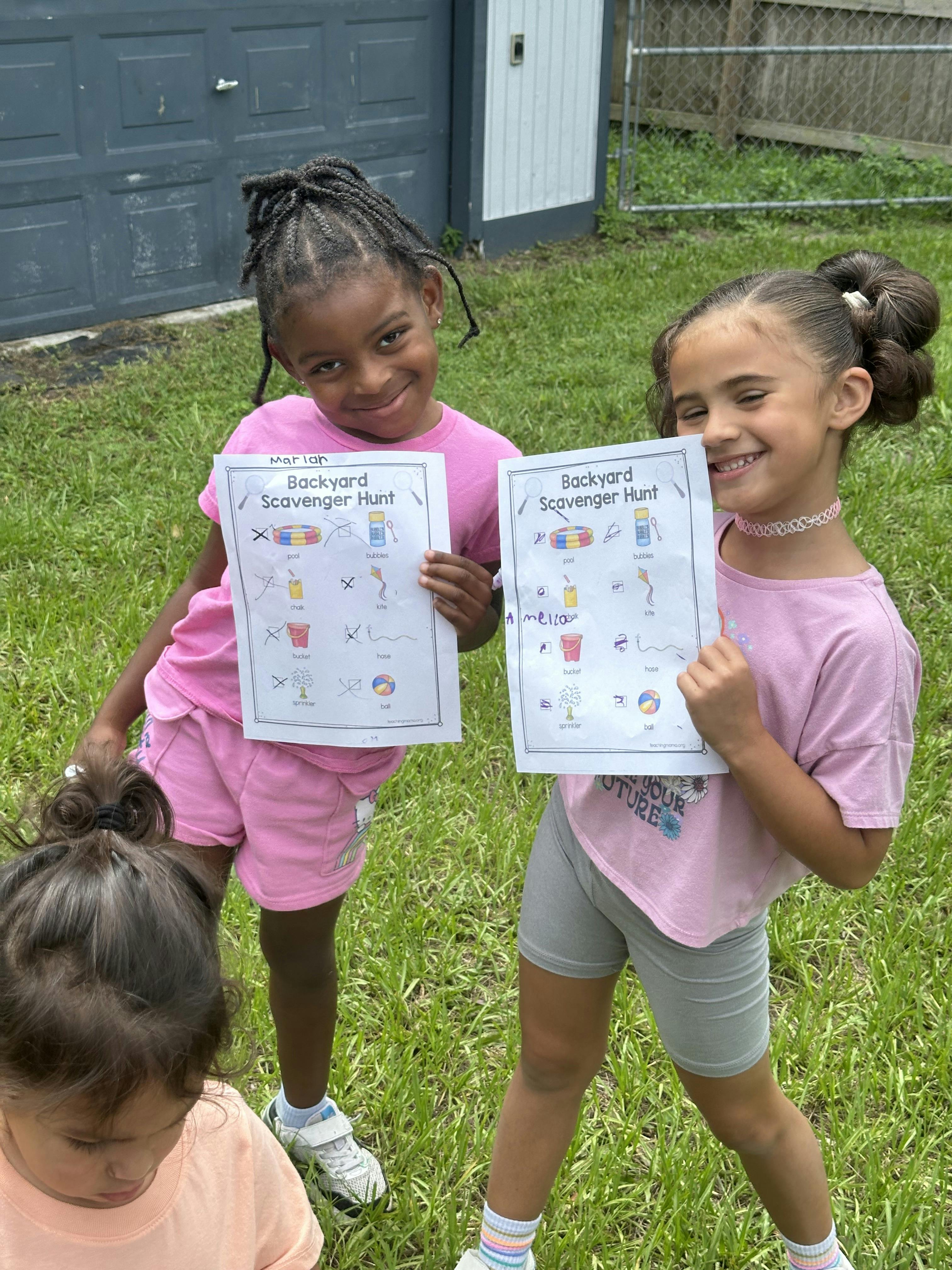 Two children holding Backyard Scavenger Hunt papers