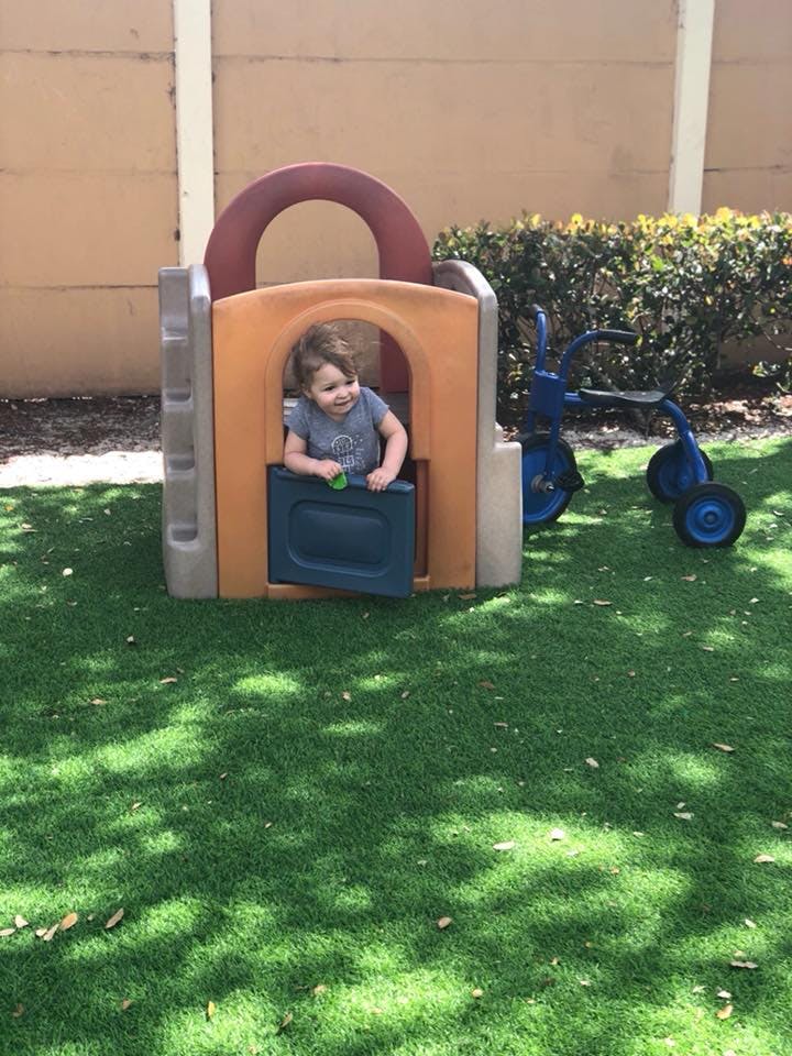Child in a playhouse window on artificial grass