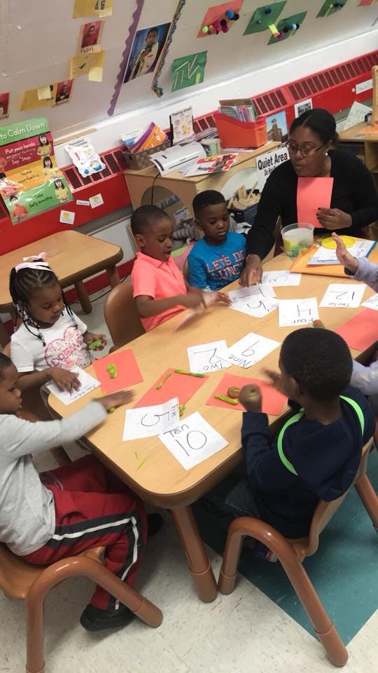 Adult and children sitting at a table with papers and crayons