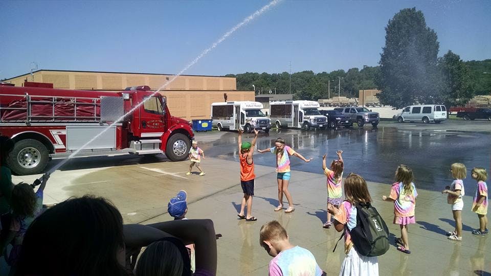 Children playing in water from a fire truck hose